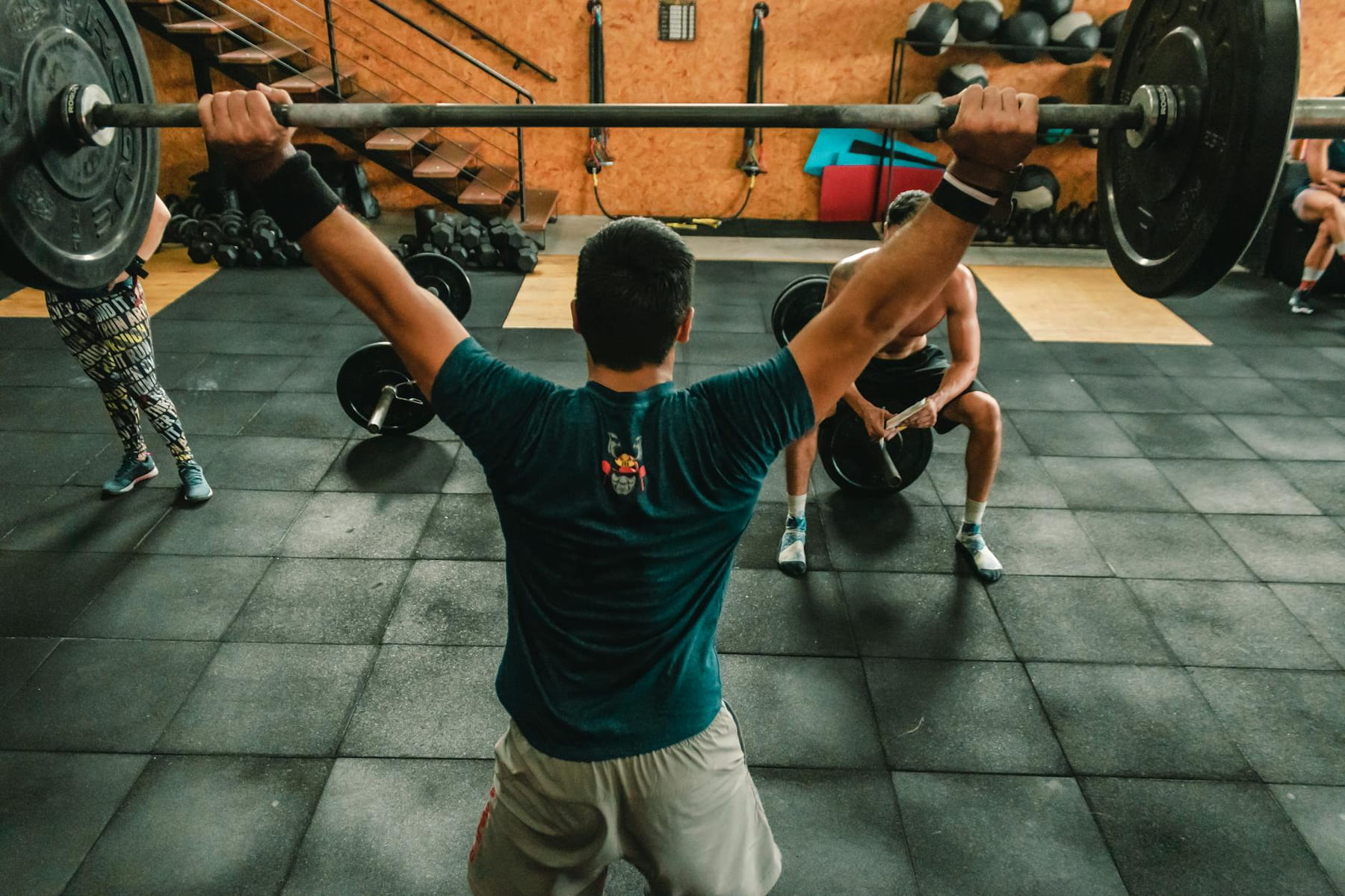 A group of men engaged in a vigorous weightlifting session at a gym. on First Rep Forward