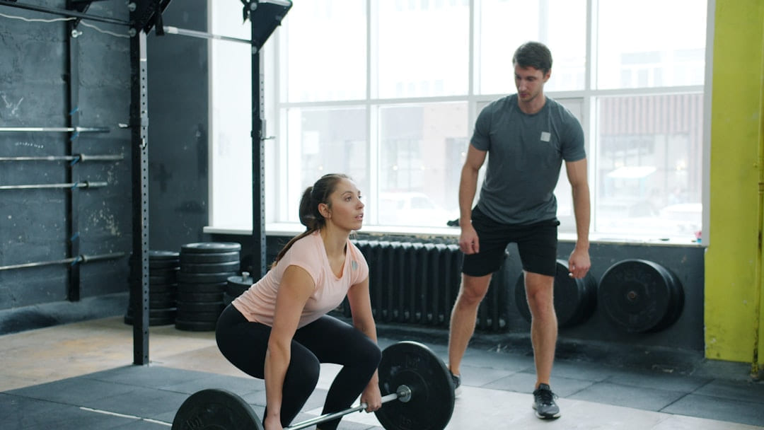 Woman lifting weights with trainer watching on First Rep Forward