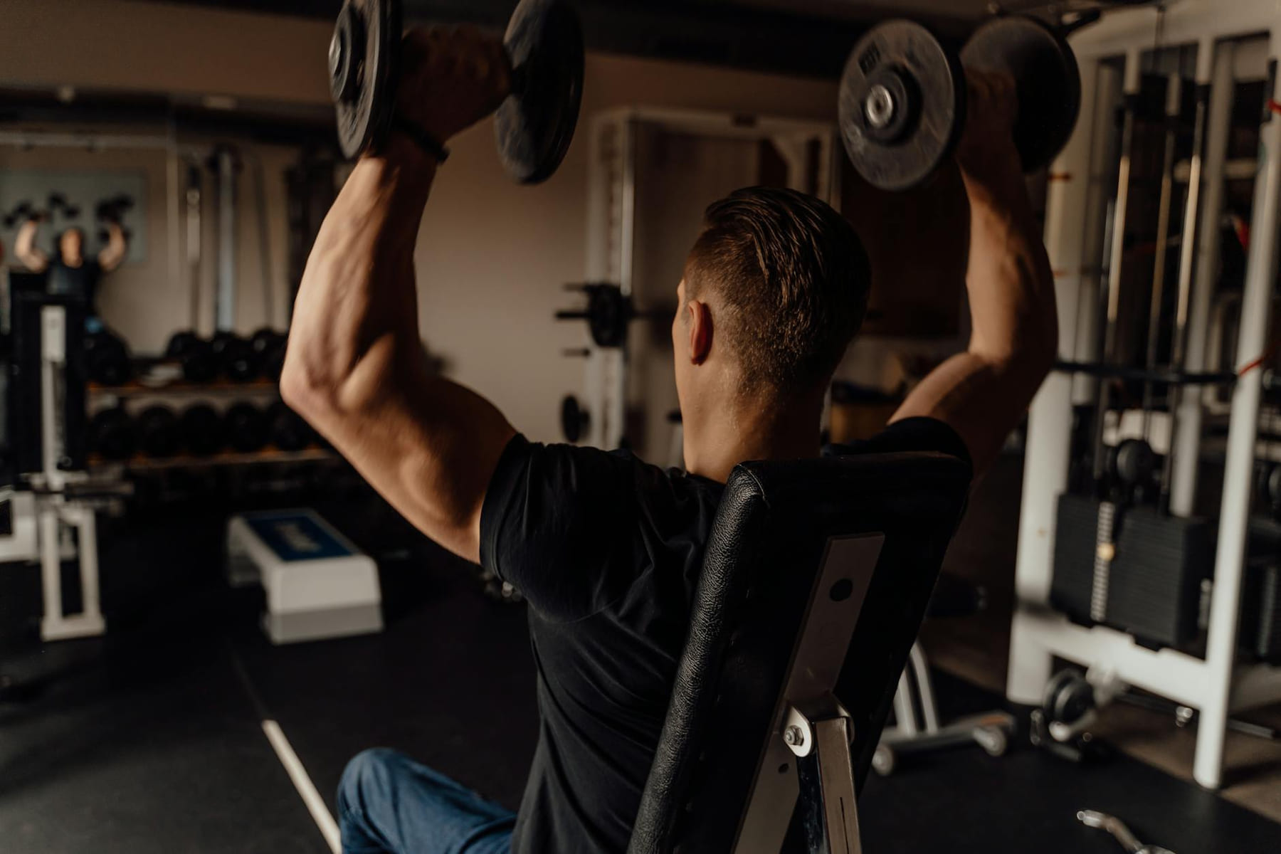 Adult man exercising with dumbbells in a gym, focused on fitness training. on First Rep Forward
