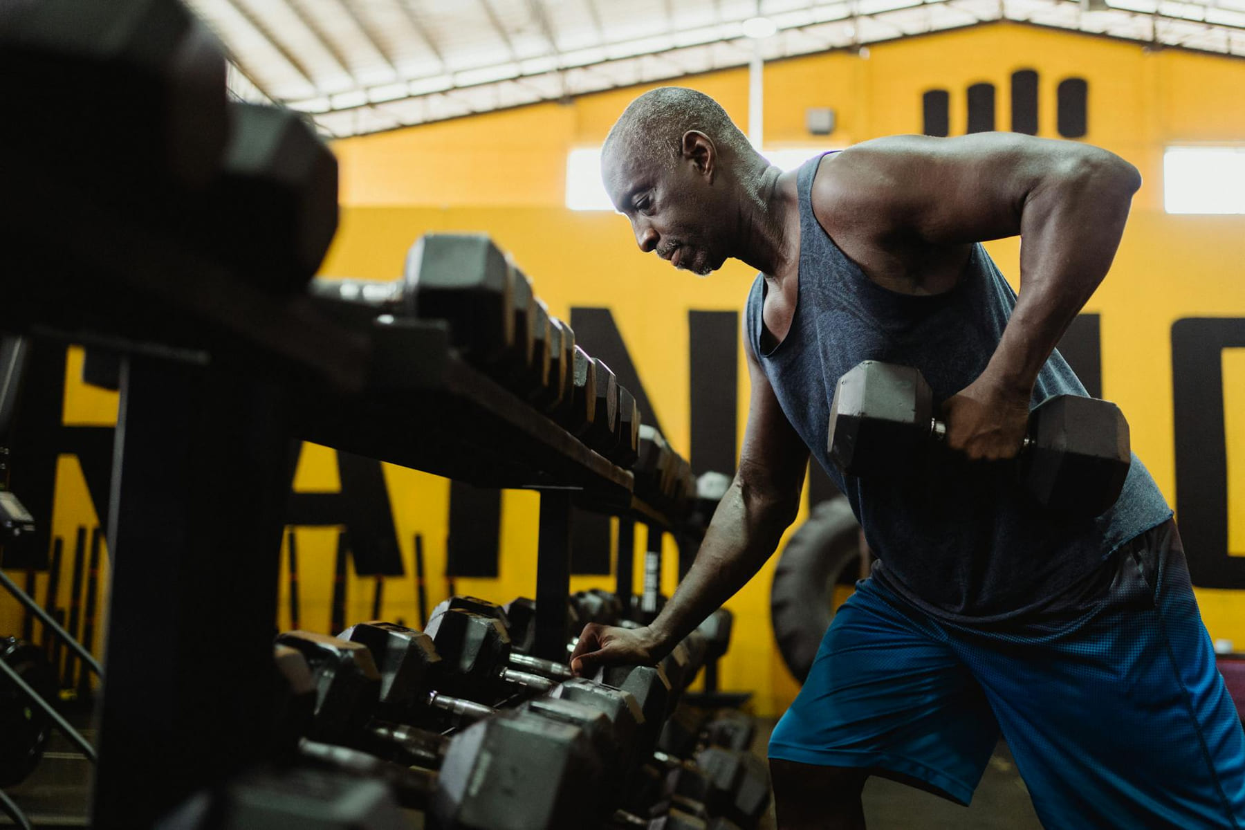 Athletic man lifting dumbbells in a gym for strength training workout. on First Rep Forward
