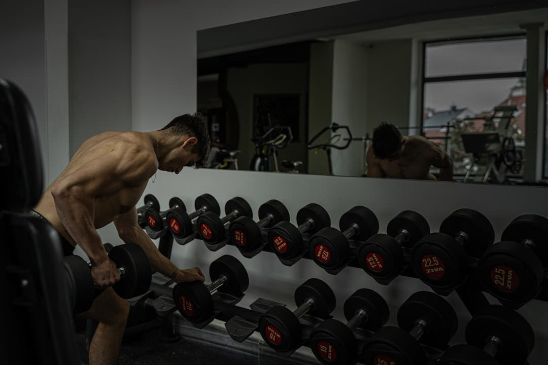 Man at the gym choosing a dumbbell. on First Rep Forward