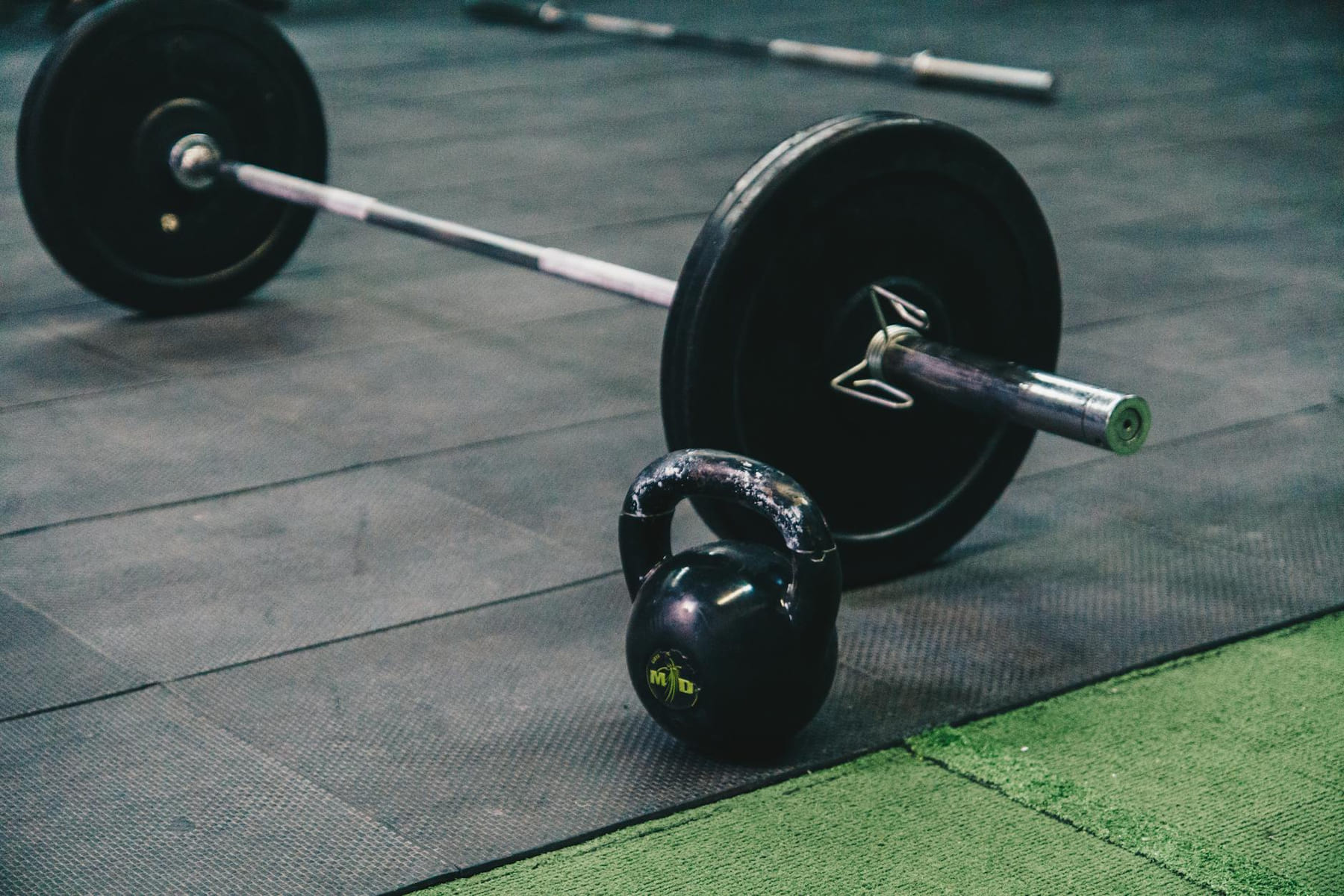 Barbell and kettlebell on gym floor, ideal for fitness and strength training themes. on First Rep Forward