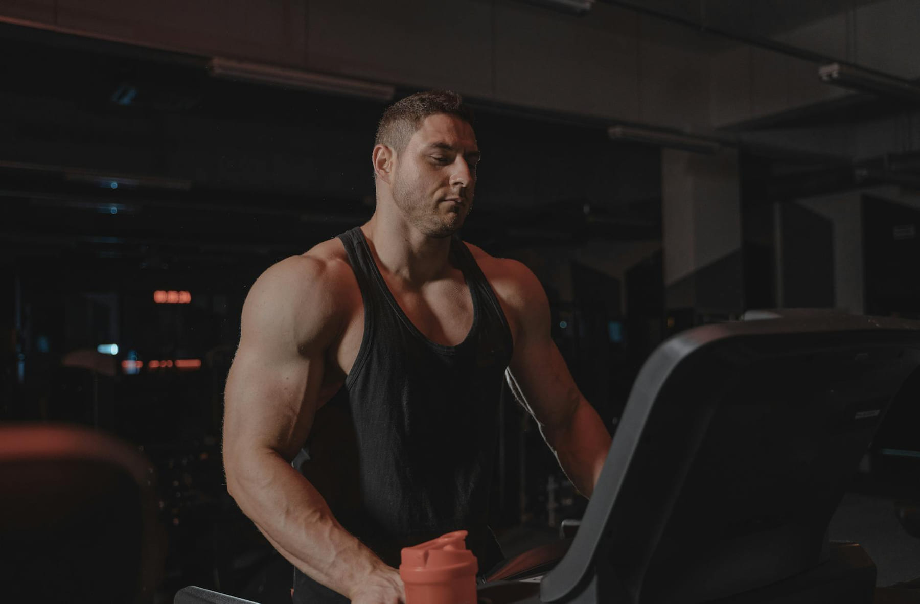 A bodybuilder working out on a treadmill at the gym, focused on fitness and strength training. on First Rep Forward